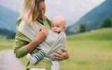 Babywearing. Mother and baby on nature outdoors. Baby in wrap carrier.