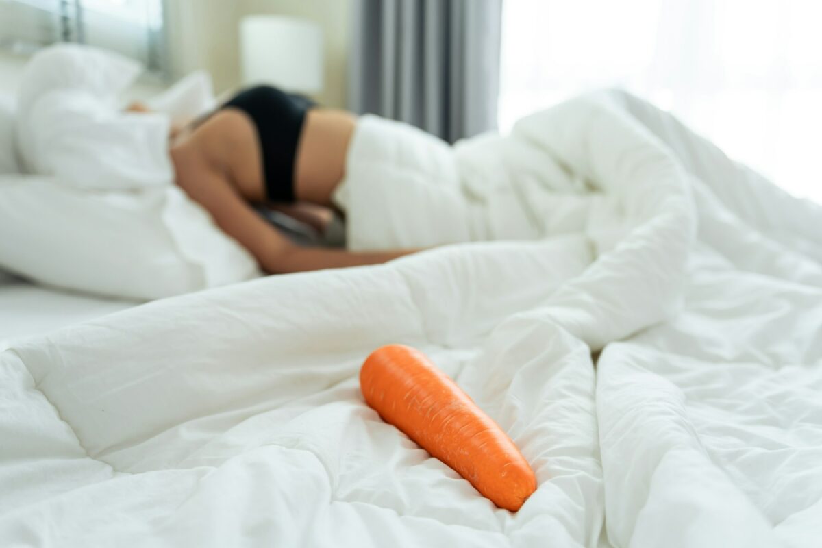 Close up of cucumber foods for erotic sex education on bed in bedroom.