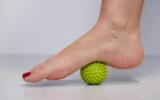 foot step on massage ball to relieve Plantar fasciitis or heel pain. woman with red