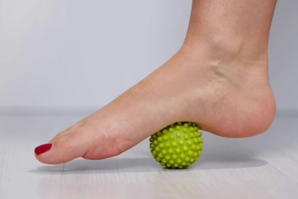 foot step on massage ball to relieve Plantar fasciitis or heel pain. woman with red