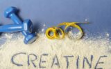 word creatine written on creatine powder on blue background