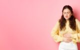 Young woman with pain in stomach, holding hands on belly, feeling terrible ache, menstrual cramps