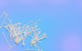 Ear sticks on blue purple background. Makeup removal and skin care concept. Space for text