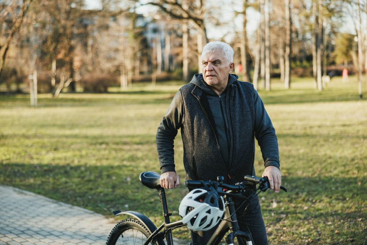 Man Walking a Bike Down a Sidewalk In City Park