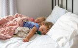 Two little girls napping on a big white bed