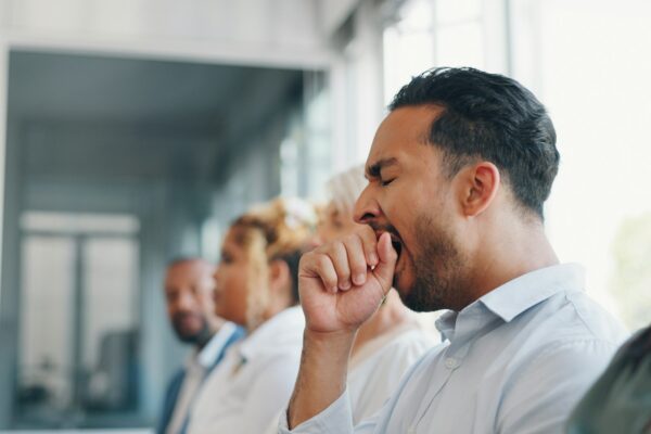 Tired, yawn and sleepless with a business man sitting in a meeting or presentation with his team fo