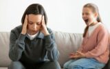 Unhappy caucasian middle aged mother suffers from screams and whims of daughter in living room