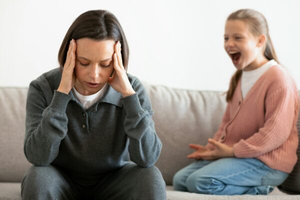 Unhappy caucasian middle aged mother suffers from screams and whims of daughter in living room
