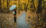 Girl with umbrella on the autumnal colorful forest path