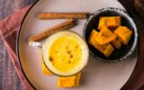Pumpkin latte in glasses and pieces of pumpkin in a bowl. Homemade autumn drinks. Top view. Closeup