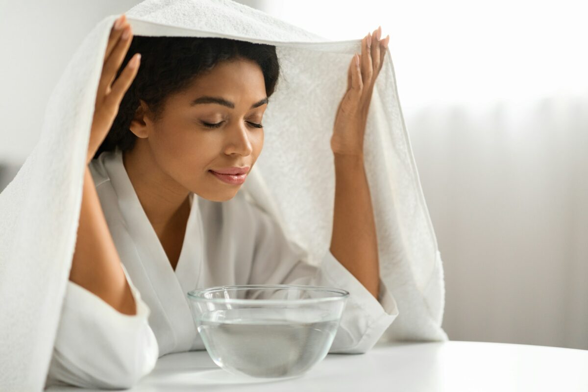 Beauty Hacks. Young black woman inhaling steam of hot water at home
