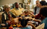 Happy woman passing food to her family while celebrating Thanksgiving at home.