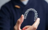 Man holding one transparent aligner. Invisalign orthodontics concept