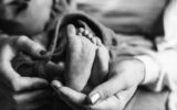 Mother holding newborn baby Feet after birth black and white