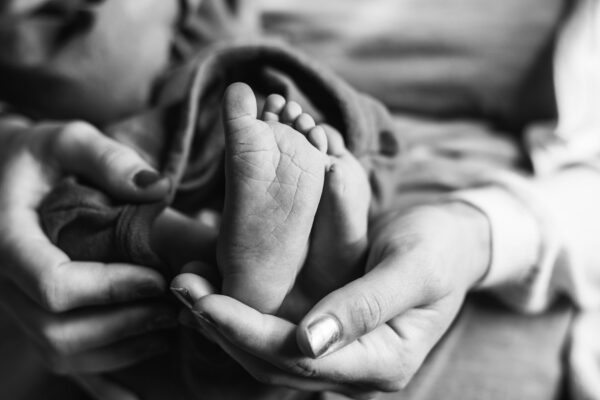 Mother holding newborn baby Feet after birth black and white