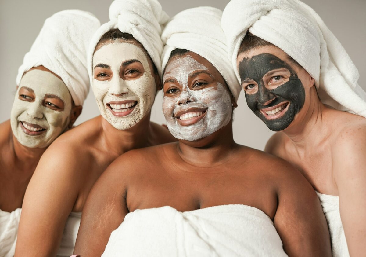 Multiracial women enjoy spa day together with beauty face mask while wearing towels