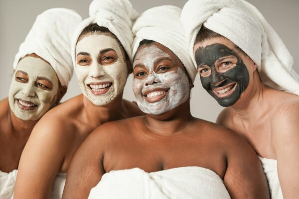 Multiracial women enjoy spa day together with beauty face mask while wearing towels