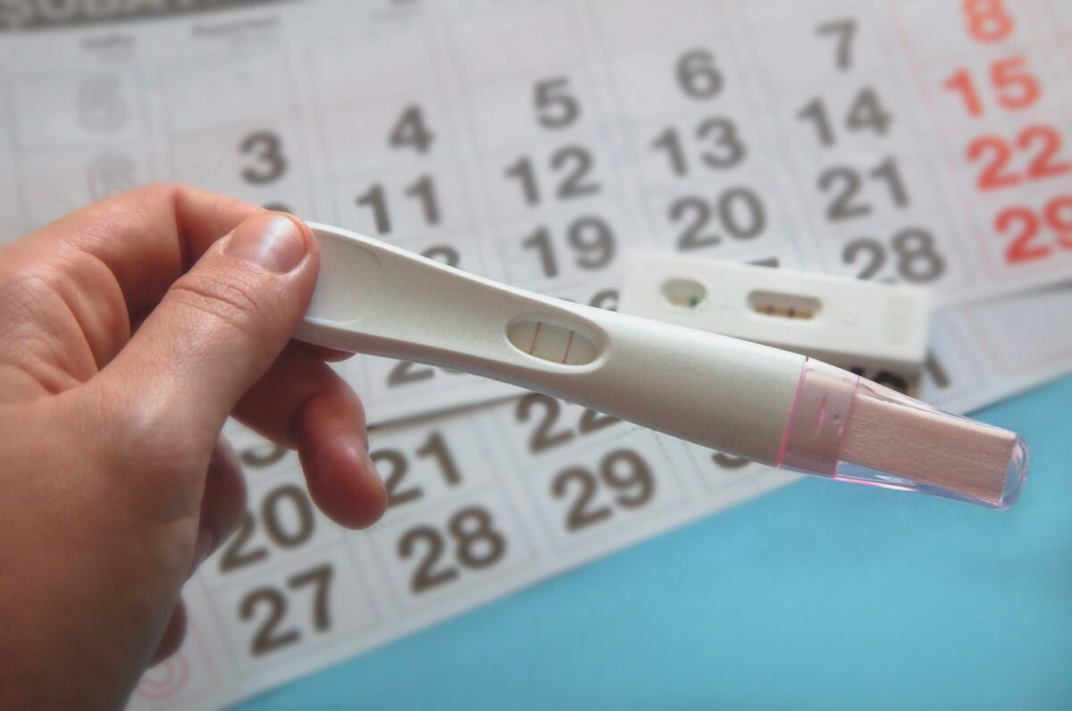 Person holding a positive Pregnancy test on calendar background