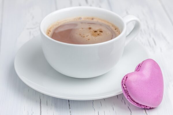 A cup of hot chocolate with a heart-shaped macaron