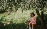 Asian girl sitting on stepladder under an apple tree