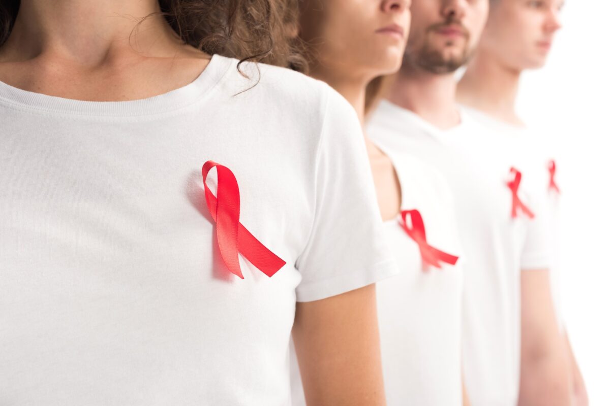 cropped image of people standing with red ribbons on white shirts isolated on white, world aids day