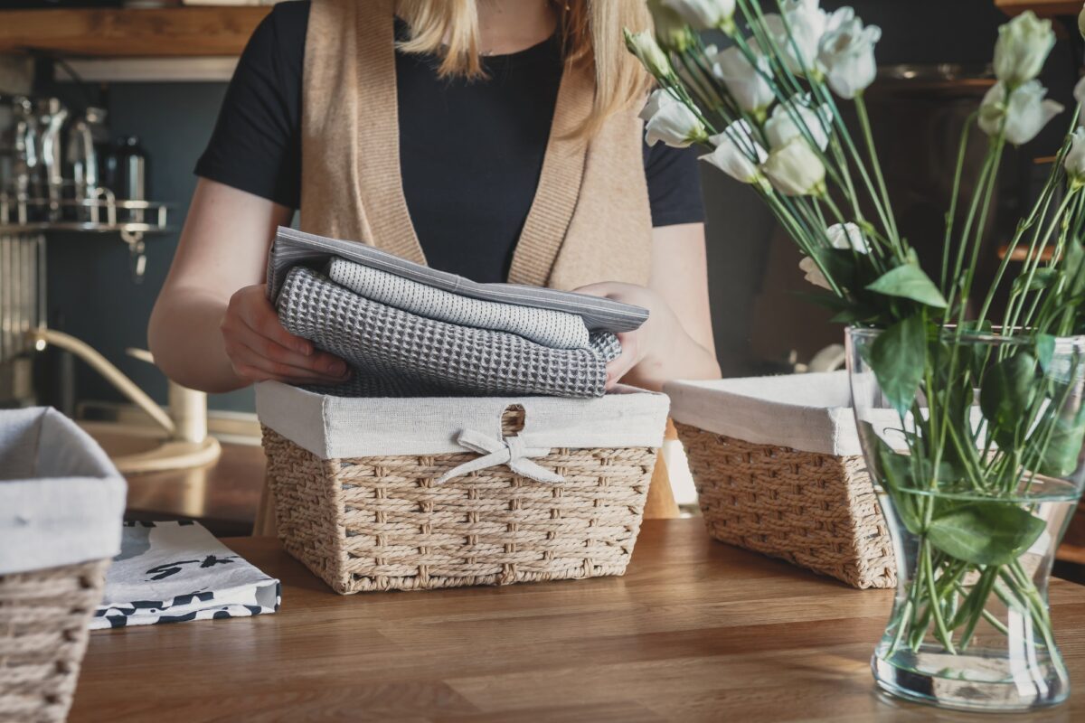 Girl spring cleaning in the kitchen. Piles kitchen towels in baskets. Spring cleaning, decluttering