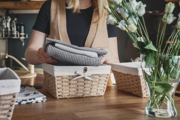 Girl spring cleaning in the kitchen. Piles kitchen towels in baskets. Spring cleaning, decluttering