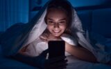 Happy woman watching video on cellphone at night